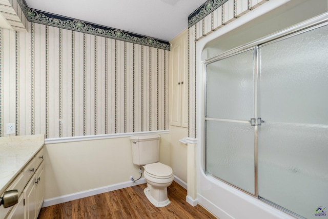 full bathroom featuring shower / bath combination with glass door, hardwood / wood-style floors, vanity, and toilet