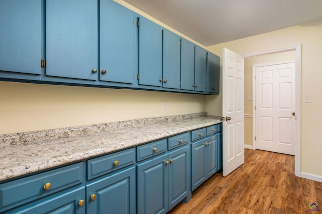 kitchen with dark hardwood / wood-style flooring, a textured ceiling, and blue cabinets