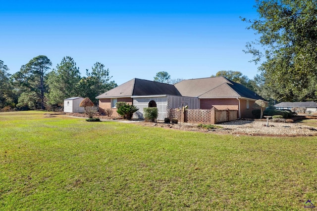 ranch-style house featuring a front lawn and a storage shed