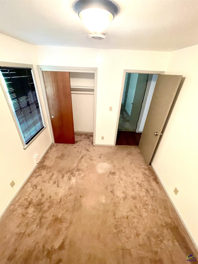 unfurnished bedroom featuring visible vents, a closet, and light colored carpet