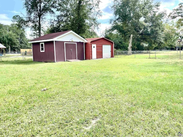 view of yard featuring a detached garage, fence, and an outdoor structure