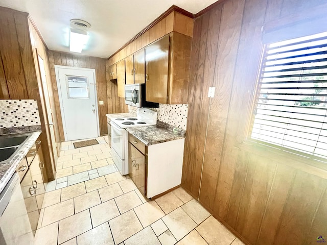 kitchen featuring tasteful backsplash, visible vents, brown cabinetry, wooden walls, and white appliances