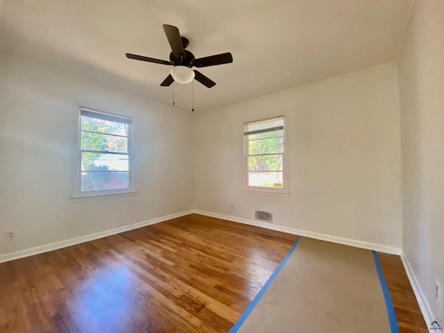 spare room with dark hardwood / wood-style floors, ceiling fan, and a wealth of natural light