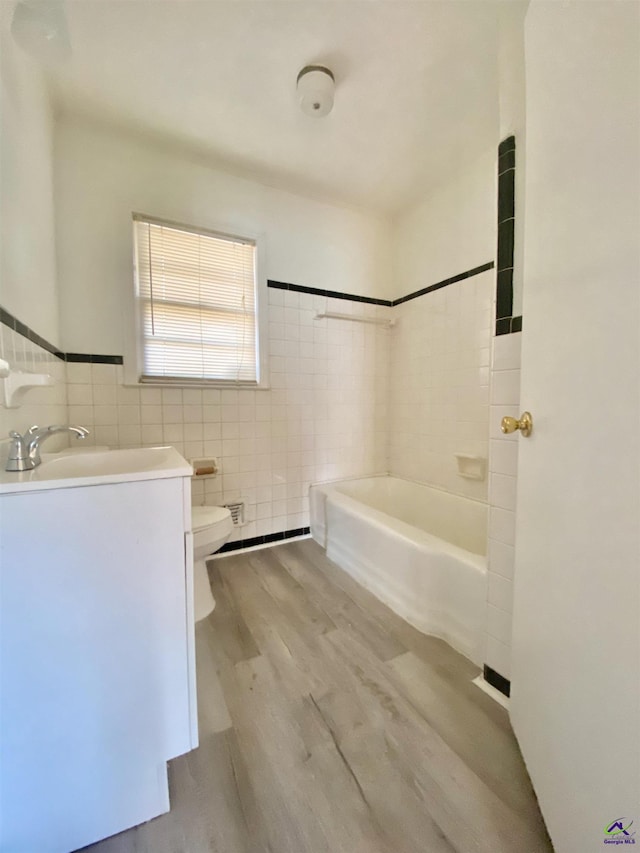 full bath with toilet, wood finished floors, tile walls, tub / shower combination, and vanity