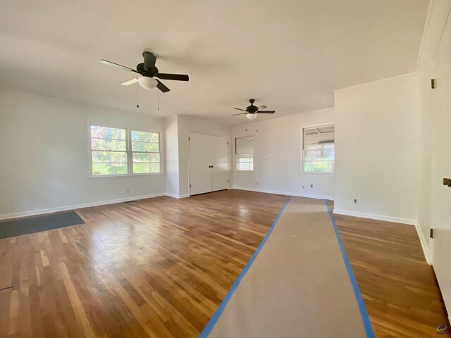 interior space with a ceiling fan, wood finished floors, and baseboards