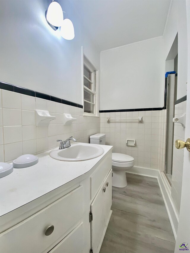 full bathroom with toilet, a stall shower, wood finished floors, tile walls, and vanity