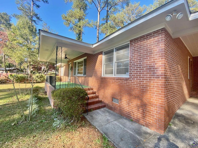 view of property exterior with a porch, brick siding, and crawl space