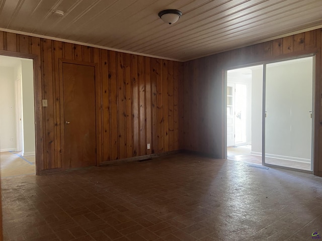 spare room featuring wooden ceiling, wood walls, and ornamental molding