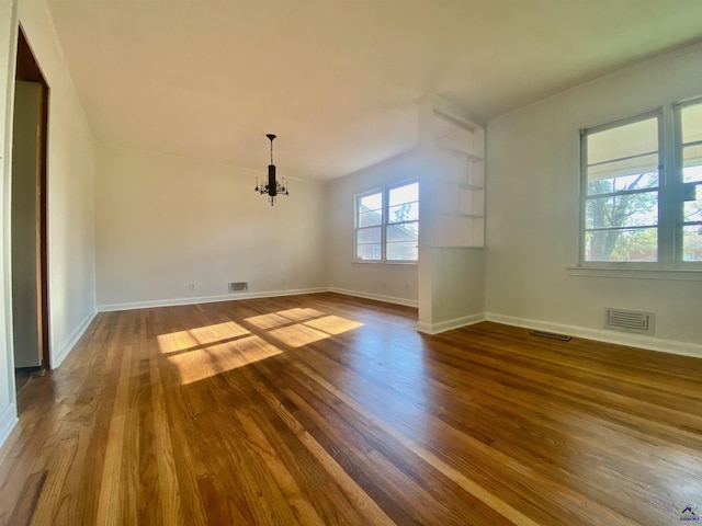 interior space with dark wood-type flooring, a notable chandelier, baseboards, and visible vents