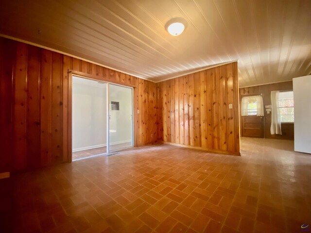 empty room featuring brick floor and wood walls