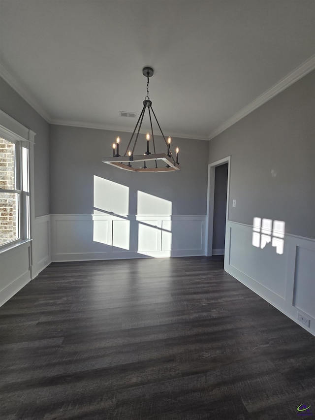 unfurnished dining area featuring dark wood-type flooring, crown molding, and an inviting chandelier