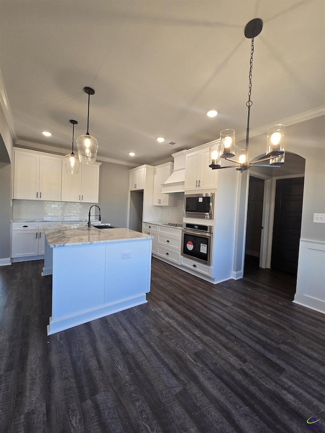 kitchen with appliances with stainless steel finishes, decorative light fixtures, white cabinetry, and light stone counters