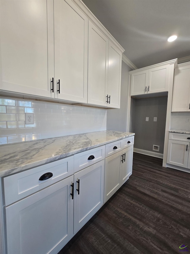 kitchen with light stone countertops, dark hardwood / wood-style flooring, white cabinetry, and ornamental molding