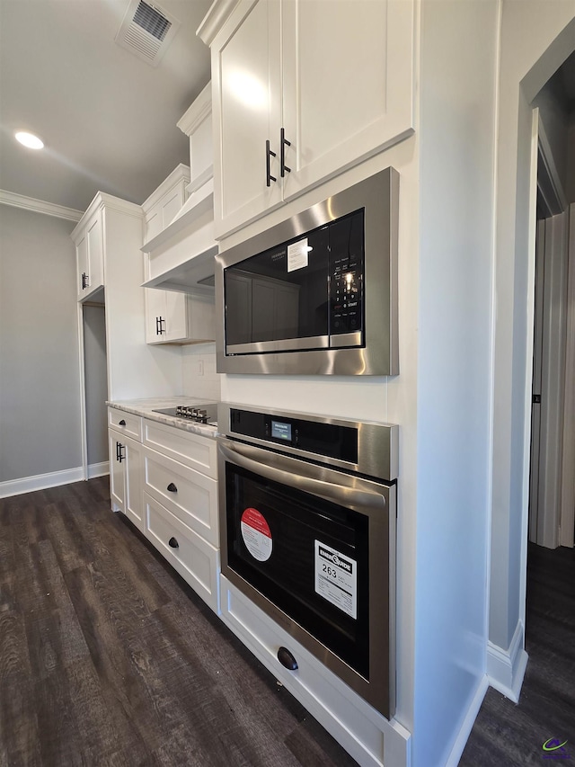 kitchen with ornamental molding, stainless steel appliances, white cabinetry, and dark wood-type flooring