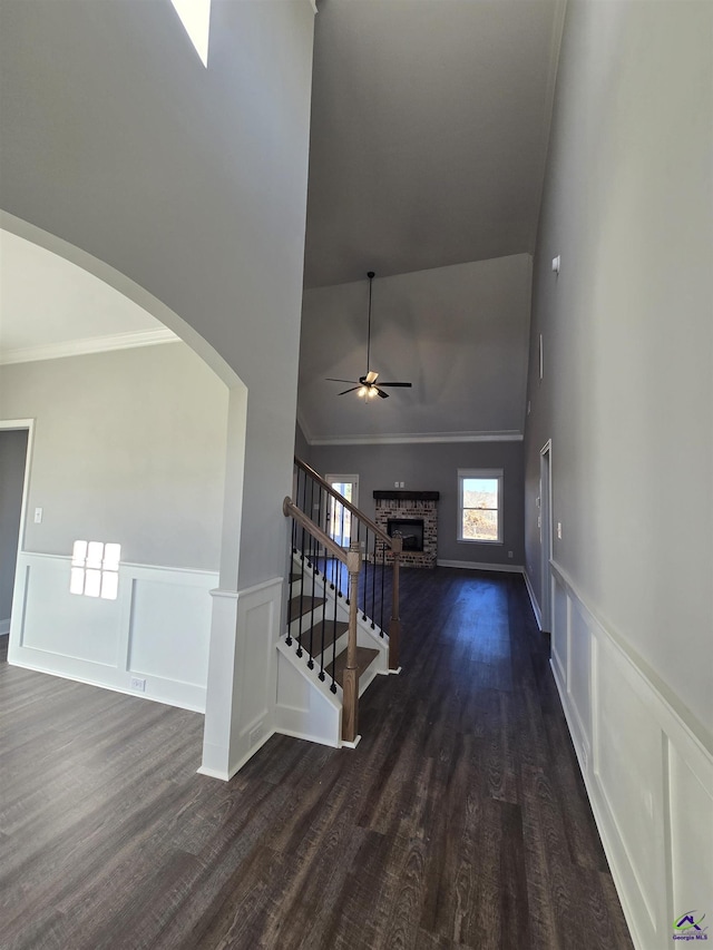 interior space featuring ceiling fan, a stone fireplace, wood-type flooring, and ornamental molding