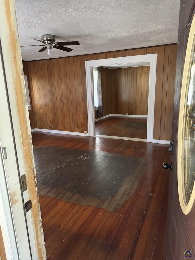 foyer featuring a textured ceiling, dark hardwood / wood-style floors, and wood walls