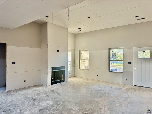 unfurnished living room featuring a fireplace and a high ceiling