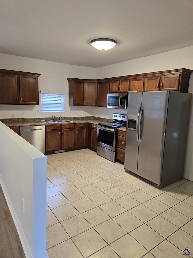 kitchen featuring sink, light tile patterned floors, dark brown cabinets, and appliances with stainless steel finishes