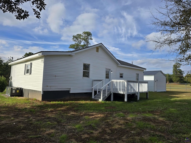 rear view of property featuring central AC, a shed, a deck, and a lawn