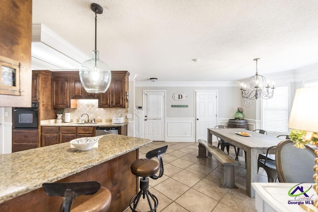 kitchen with dishwasher, an inviting chandelier, backsplash, pendant lighting, and a breakfast bar