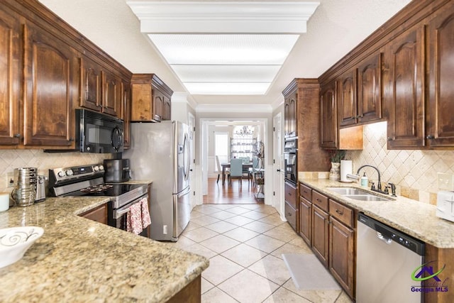 kitchen with backsplash, light stone countertops, sink, and black appliances