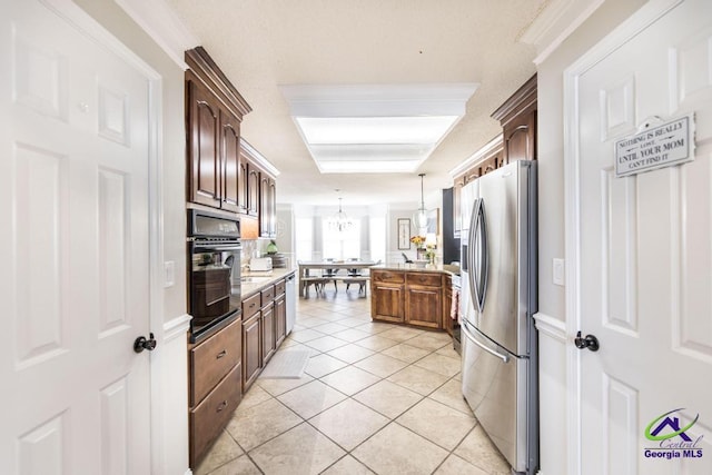 kitchen with light stone counters, stainless steel appliances, light tile patterned floors, a notable chandelier, and hanging light fixtures