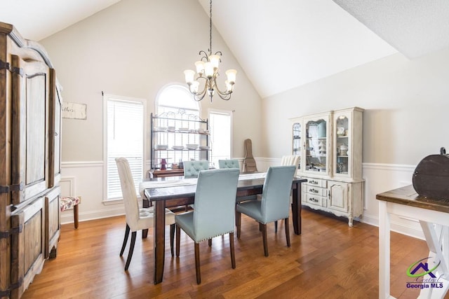 dining space featuring hardwood / wood-style floors, high vaulted ceiling, and a chandelier