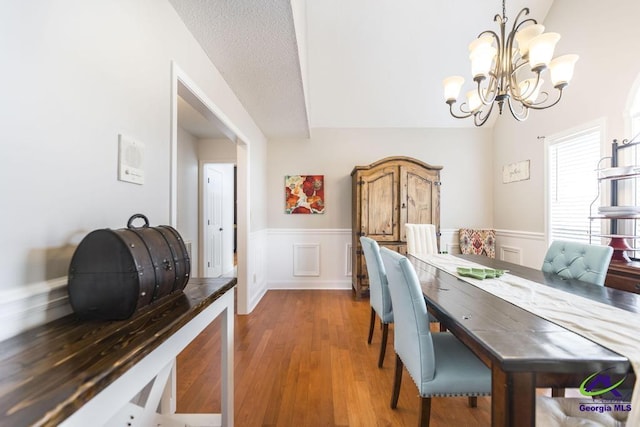 dining space featuring a textured ceiling, hardwood / wood-style flooring, and an inviting chandelier