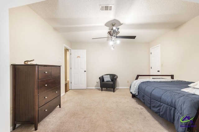 carpeted bedroom featuring ceiling fan and a textured ceiling