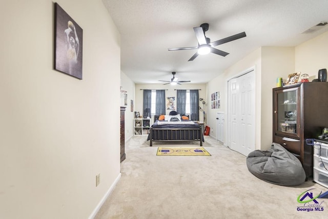 carpeted bedroom with ceiling fan, a closet, and a textured ceiling