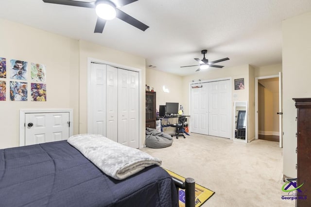 carpeted bedroom with ceiling fan and two closets