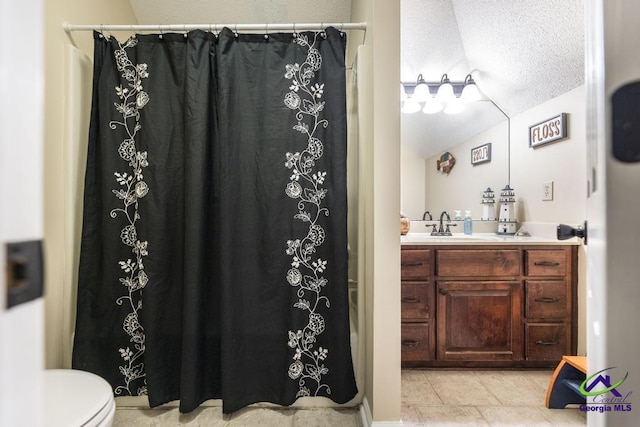 bathroom with tile patterned flooring, lofted ceiling, a textured ceiling, toilet, and vanity