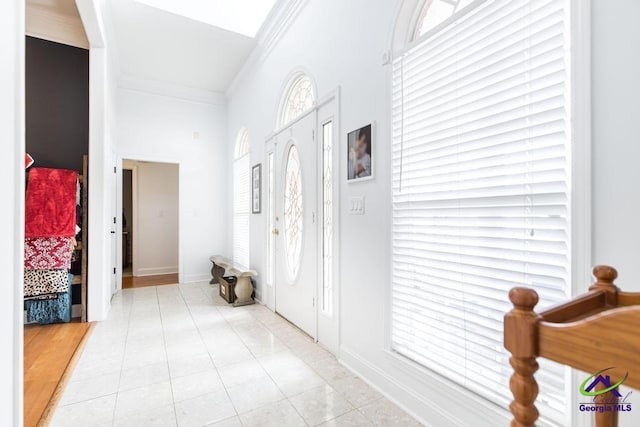 foyer with crown molding and light tile patterned floors