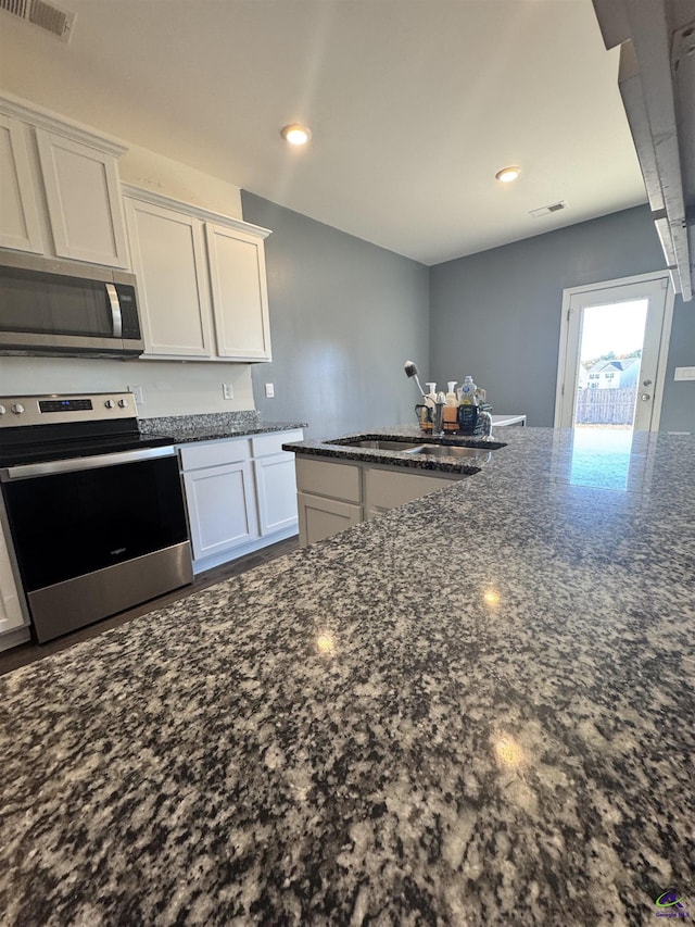 kitchen with white cabinetry, sink, appliances with stainless steel finishes, and dark stone counters