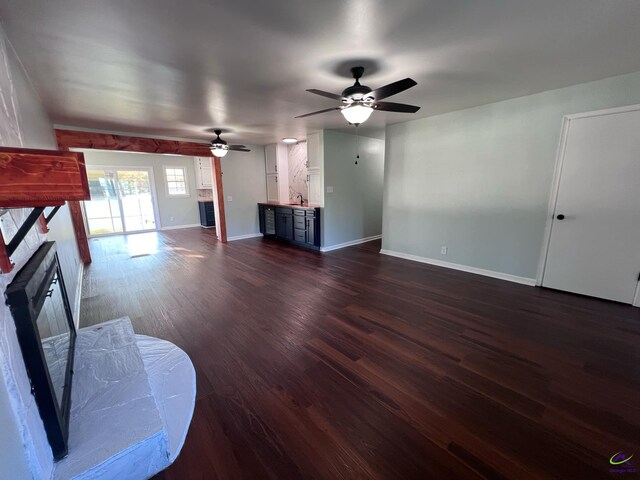 unfurnished living room featuring ceiling fan and dark wood-type flooring