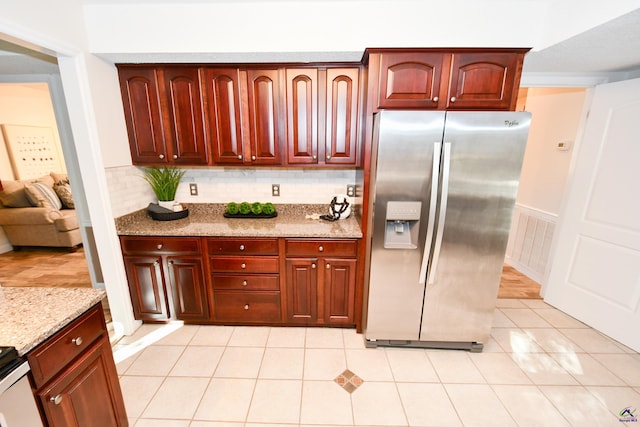 kitchen featuring stainless steel refrigerator with ice dispenser, backsplash, light stone counters, and light tile patterned floors