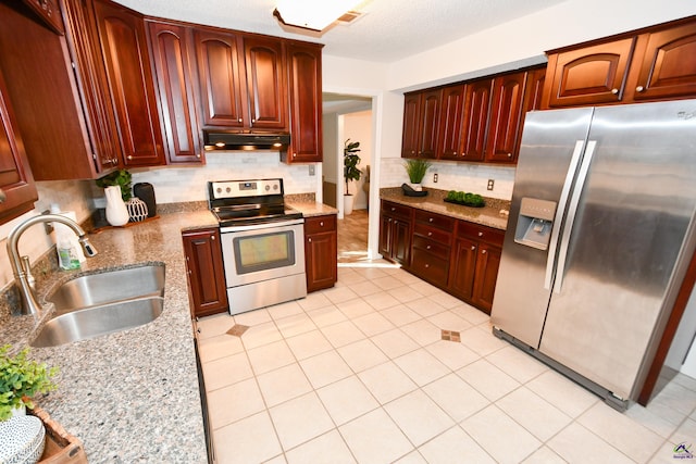 kitchen with light tile patterned floors, stainless steel appliances, light stone counters, and sink