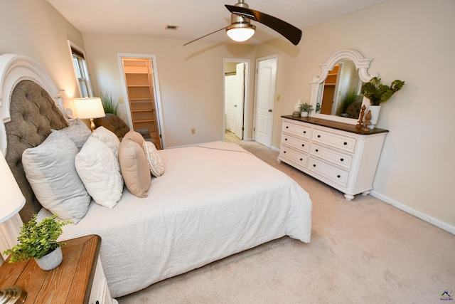 carpeted bedroom with a walk in closet, a closet, and ceiling fan