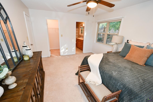 bedroom with ensuite bath, ceiling fan, a spacious closet, light colored carpet, and a closet