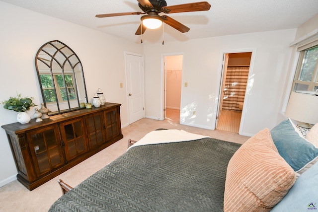 carpeted bedroom featuring multiple windows, ensuite bathroom, ceiling fan, and a walk in closet