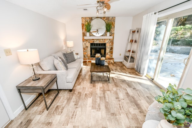 living room with a fireplace, light wood-type flooring, vaulted ceiling, and ceiling fan