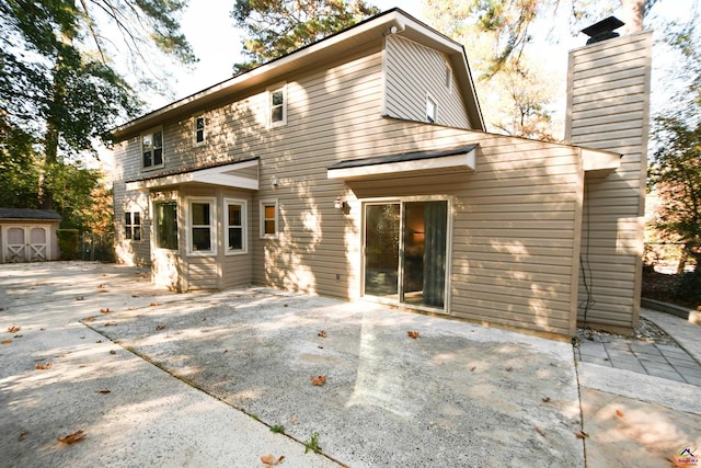 back of house featuring a storage unit and a patio area