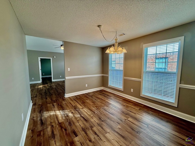 unfurnished dining area featuring hardwood / wood-style floors, ceiling fan with notable chandelier, and a textured ceiling