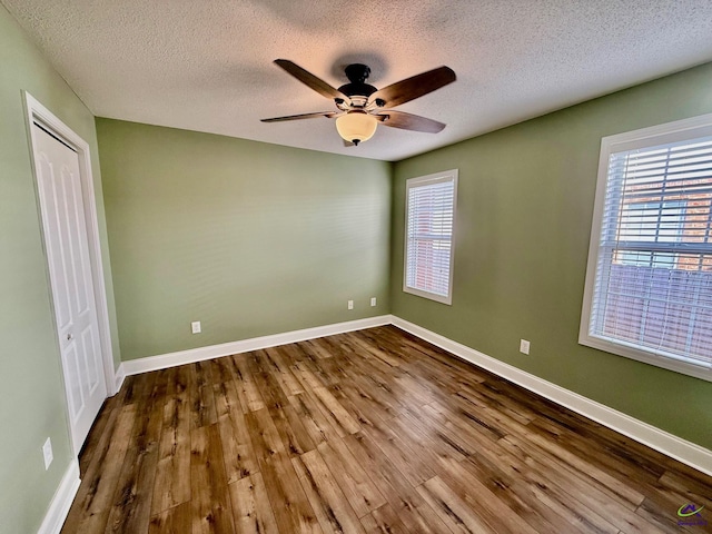 unfurnished bedroom with hardwood / wood-style floors, a textured ceiling, a closet, and ceiling fan