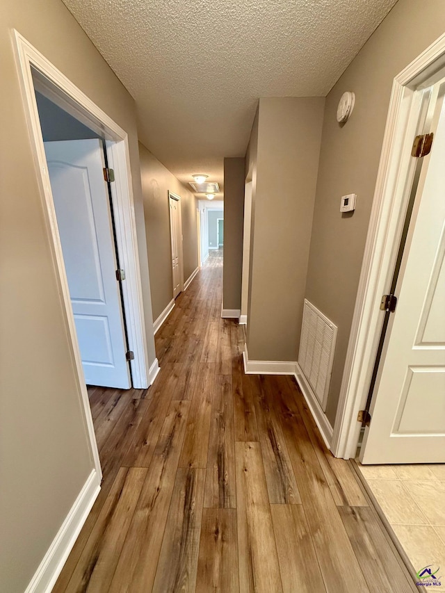 corridor featuring wood-type flooring and a textured ceiling