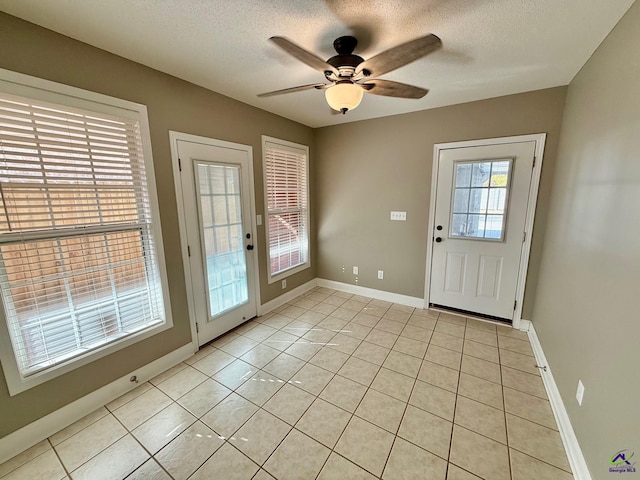 doorway with a wealth of natural light, light tile patterned flooring, and a textured ceiling