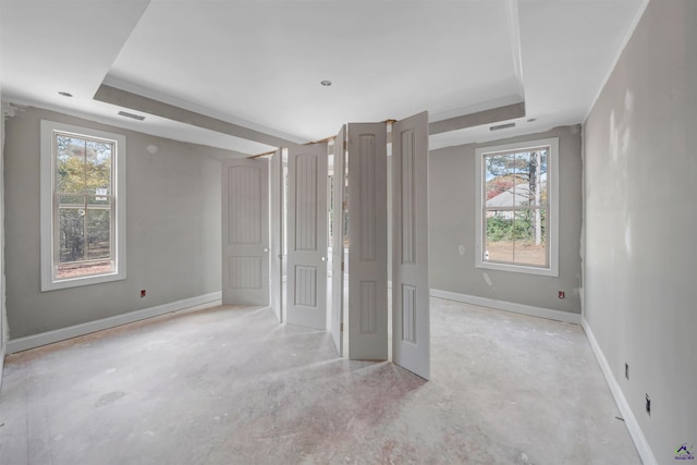 unfurnished bedroom featuring a tray ceiling and multiple windows