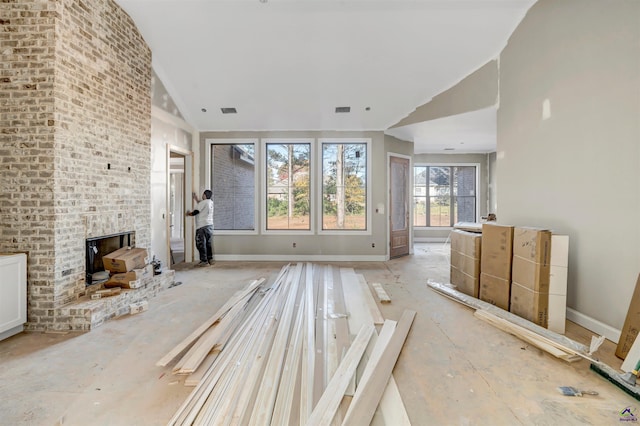 unfurnished living room with a brick fireplace and vaulted ceiling