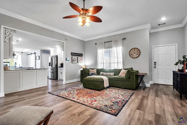 living room featuring ceiling fan, crown molding, wood-type flooring, and a textured ceiling