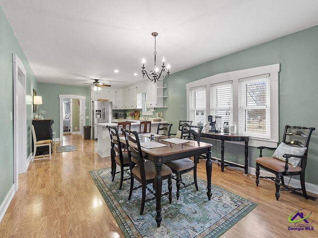 dining room with ceiling fan with notable chandelier and light hardwood / wood-style floors